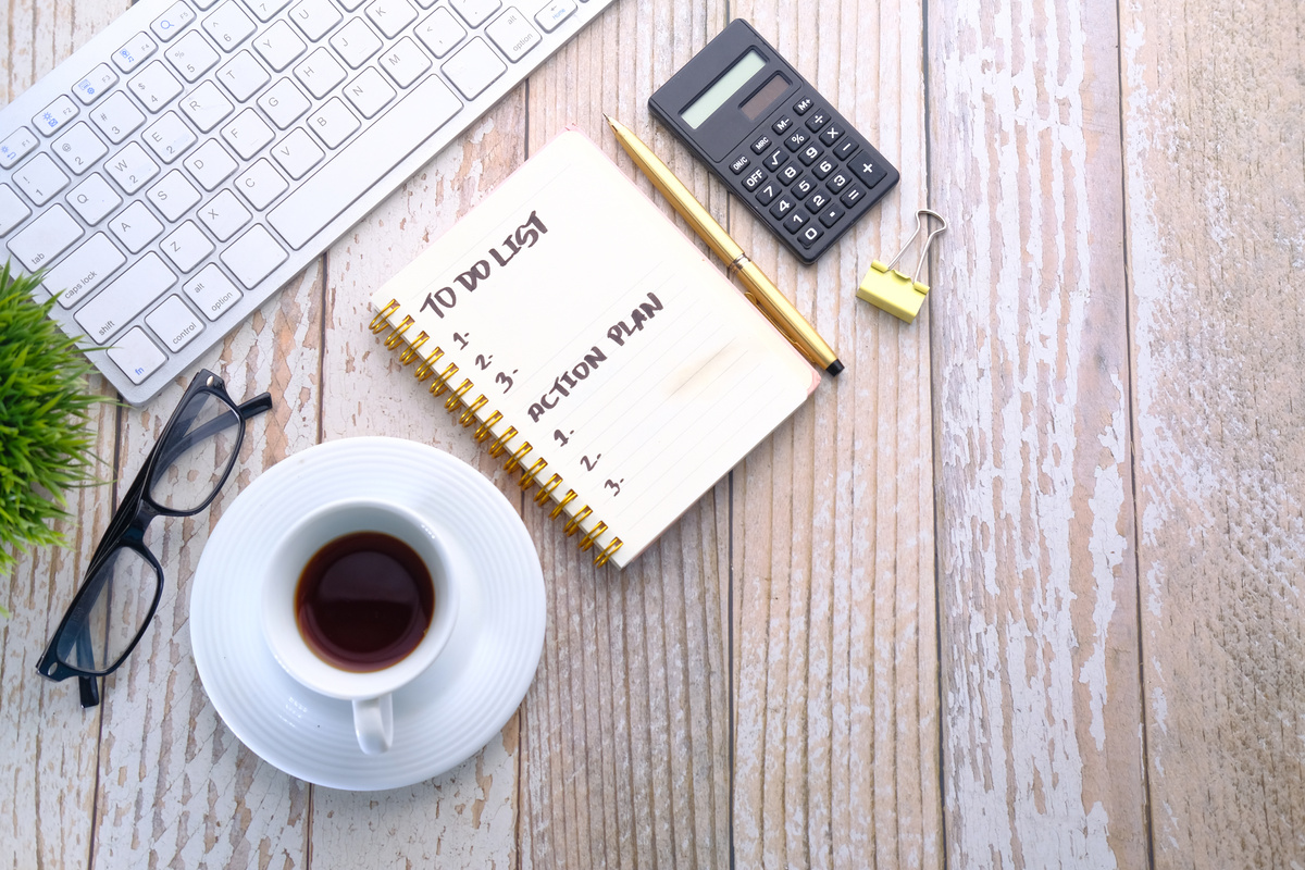 Coffee Cup and Notebook with to Do List on on Wooden Table